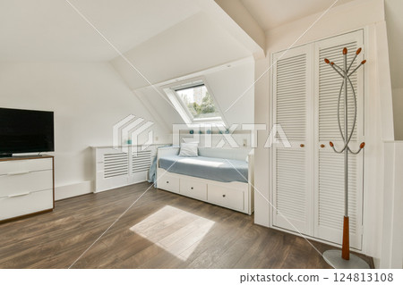 A modern bedroom featuring a cozy bed, minimalist decor, and ample natural light filtering through the windows. The wooden floor adds warmth to the space. 124813108
