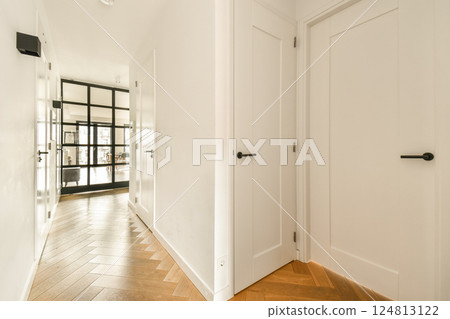 A sleek and modern hallway featuring stylish doors and a warm wooden floor, creating an inviting atmosphere. Natural light enhances the minimalist design. A sleek and modern hallway featuring stylish doors and a warm wooden floor, creating an inviting atmosphere. Natural light enhances the minimalist design. 124813122