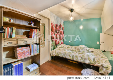 A bright, inviting bedroom featuring a bed adorned with floral bedding, a wooden shelf filled with books, and tulip artwork on the walls. 124813141