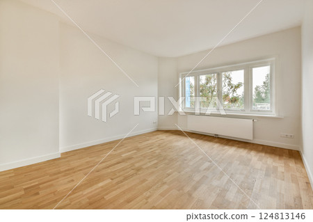 A bright and airy room showcasing minimalistic interior design with natural light streaming through large windows and elegant wooden flooring. 124813146