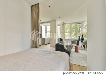 A spacious modern interior showcases large windows letting in abundant natural light. The design combines comfort and elegance with stylish furnishings. A spacious modern interior showcases large windows letting in abundant natural light. The design combines comfort and elegance with stylish furnishings. 124813227