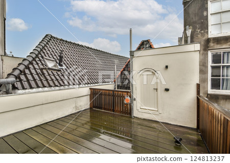 A stylish modern rooftop terrace featuring wooden flooring and rooftop access, complemented by a beautifully designed exterior wall in a lively urban setting. 124813237