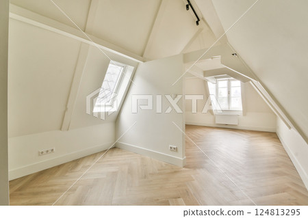 A modern interior featuring angled ceilings, large windows, and wooden flooring that creates a warm and inviting atmosphere. Ideal for contemporary living spaces. 124813295