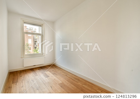 A bright and empty room featuring light wood flooring, large window, and minimalist design. Perfect for various interior themes and decor styles. 124813296