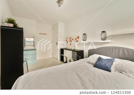 A serene and modern bedroom featuring minimalist design elements, soft textures, and a soothing color palette, ideal for relaxation and comfort. 124813300