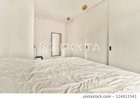 A serene minimalist bedroom featuring a simple layout, white bedding, and subtle lighting. The design emphasizes tranquility and simplicity in modern living spaces. 124813341