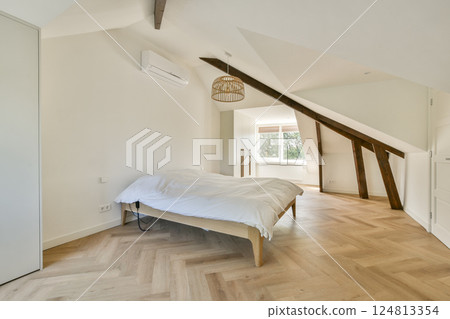 A spacious minimalist bedroom showcasing natural light, wooden flooring, and a cozy bed, reflecting a calm and serene atmosphere. A spacious minimalist bedroom showcasing natural light, wooden flooring, and a cozy bed, reflecting a calm and serene atmosphere. 124813354