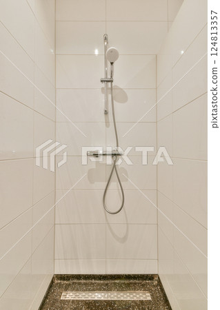 A sleek and minimalist shower setup featuring a modern showerhead and clean white tiles, creating a serene and elegant bathroom atmosphere. 124813357