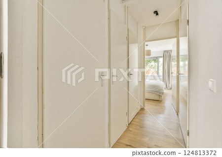 A contemporary hallway featuring white walls, wooden flooring, and natural light streaming through an open doorway, enhancing its welcoming atmosphere. A contemporary hallway featuring white walls, wooden flooring, and natural light streaming through an open doorway, enhancing its welcoming atmosphere. 124813372