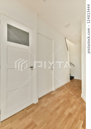 A sleek, contemporary indoor hallway featuring wooden flooring, white doors, and clean lines that enhance the airy feel of the space. A sleek, contemporary indoor hallway featuring wooden flooring, white doors, and clean lines that enhance the airy feel of the space. 124813444
