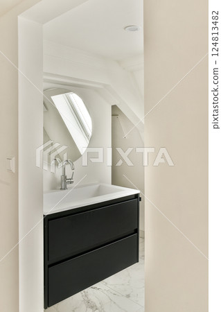 Sleek and minimalist bathroom design featuring a contemporary black vanity, stylish sink, and large mirror, complemented by light-colored walls and marble flooring. 124813482