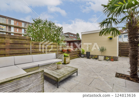 A contemporary patio setting featuring a comfortable seating area surrounded by lush greenery and modern design elements, perfect for relaxation and gatherings. 124813616