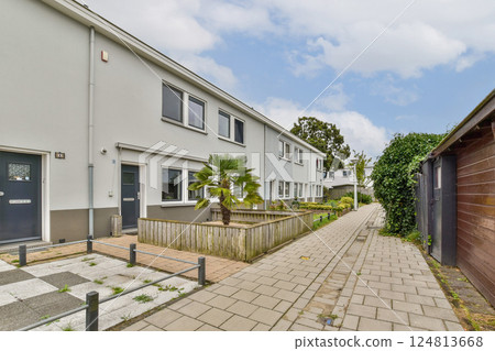 A view of modern residential buildings alongside a clean pathway and landscaping, showcasing contemporary design and outdoor space. 124813668
