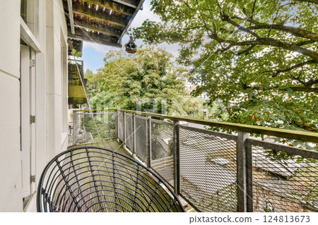 A serene balcony view showcasing a blend of natural beauty and urban elements with vibrant trees and a modern railing in sight. 124813673