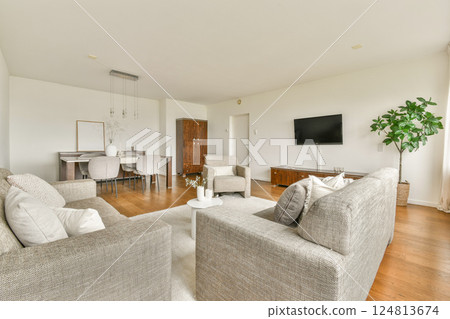 A bright and airy modern living room featuring comfortable seating, a dining area, and stylish decor, creating a cozy yet sophisticated ambiance. 124813674