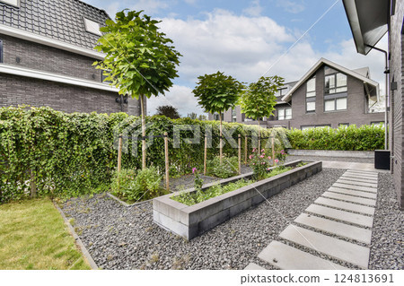 A contemporary garden featuring neatly arranged plants, stepping stone pathways, and lush greenery creates a serene outdoor space. 124813691