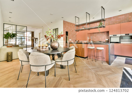 A sleek and stylish modern kitchen, featuring a dining table set with plush chairs and elegant decor, merging functionality with aesthetics in a contemporary interior design. 124813702