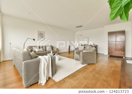 Stylish modern interior showcasing a cozy living room layout with comfortable furniture, warm wood flooring, and elegant decor. 124813723