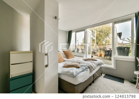 A serene bedroom featuring large windows that allow natural light to flood in. The room is decorated with soft bedding and minimal furniture, creating a peaceful atmosphere. A serene bedroom featuring large windows that allow natural light to flood in. The room is decorated with soft bedding and minimal furniture, creating a peaceful atmosphere. 124813798