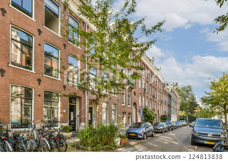 A picturesque residential area featuring brick buildings, lush trees, and bicycles lined along the walkway, creating a serene urban atmosphere. 124813838