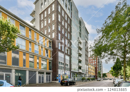A view of contemporary buildings showcasing a blend of styles, with vibrant facades and greenery along the street, reflecting city urbanization. 124813885