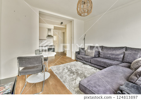 A cozy and stylish modern living room featuring a plush sofa, elegant decor, and warm wooden flooring, perfect for relaxation and social gatherings. 124813897