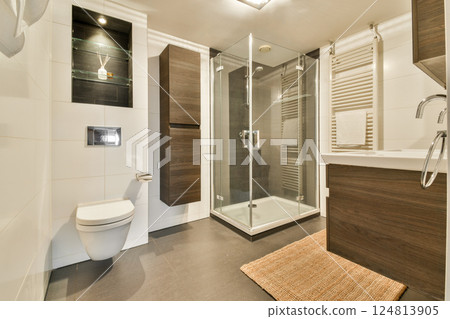 Sleek modern bathroom featuring a glass shower, contemporary fixtures, and stylish wooden accents, creating a tranquil and elegant space. 124813905