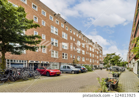 A view of a city street lined with parked bicycles, vehicles, and modern apartment buildings under a clear sky, showcasing urban lifestyle and architecture. A view of a city street lined with parked bicycles, vehicles, and modern apartment buildings under a clear sky, showcasing urban lifestyle and architecture. 124813925