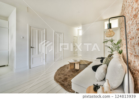 A spacious and bright living room showcasing minimalist design elements with natural light, wooden decor, and contemporary furnishings creating a warm ambiance. A spacious and bright living room showcasing minimalist design elements with natural light, wooden decor, and contemporary furnishings creating a warm ambiance. 124813939