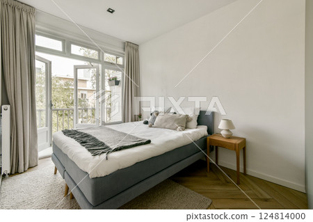 A serene modern bedroom featuring a cozy bed, elegant nightstand, and large windows that invite natural light. Simple decor enhances the calming atmosphere. A serene modern bedroom featuring a cozy bed, elegant nightstand, and large windows that invite natural light. Simple decor enhances the calming atmosphere. 124814000