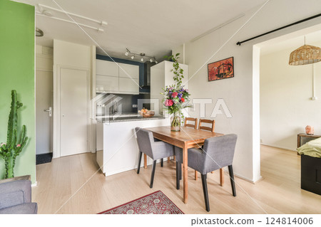 A contemporary kitchen and dining space featuring stylish furniture, a cactus plant, and vibrant flowers, creating an inviting atmosphere for meals and gatherings. 124814006