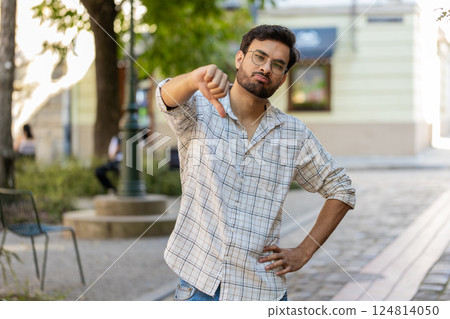 Upset Indian man showing thumb down sign gesture, expressing discontent disapproval on city street Upset Indian man showing thumb down sign gesture, expressing discontent disapproval on city street 124814050