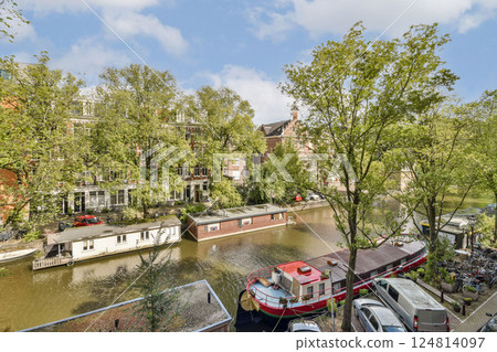 A picturesque canal scene showcases lush trees, residential buildings, and colorful boats along the waterway, ideal for relaxation and exploration. A picturesque canal scene showcases lush trees, residential buildings, and colorful boats along the waterway, ideal for relaxation and exploration. 124814097