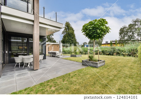 A stylish modern home featuring a beautifully landscaped garden, patio area, and vibrant greenery, creating a serene outdoor living space. A stylish modern home featuring a beautifully landscaped garden, patio area, and vibrant greenery, creating a serene outdoor living space. 124814101