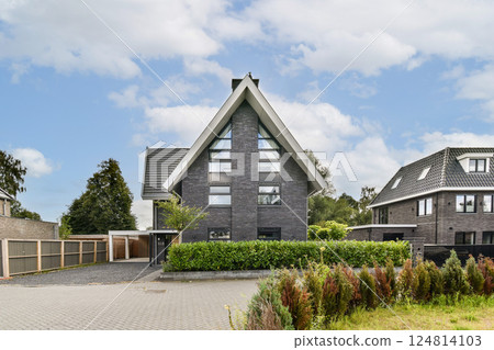 A contemporary architectural design showcases a striking house amidst vibrant landscaping and trees, reflecting elegance and style in residential living. 124814103