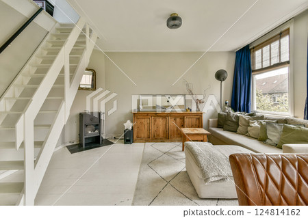 A spacious and stylish living room featuring a comfortable sofa, elegant furniture, and contemporary decor. The room showcases warm lighting and inviting atmosphere. 124814162