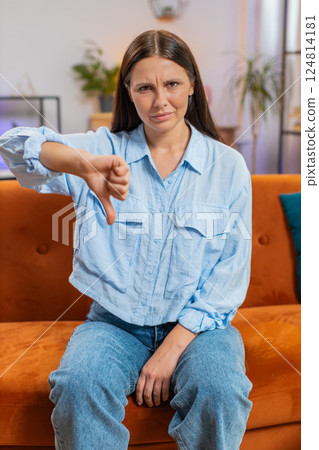 Upset unhappy young woman showing thumbs down sign dislike gesture disapproval bad work feedback 124814181