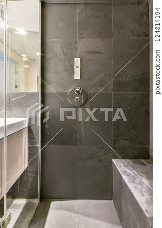 A sleek and contemporary bathroom featuring a spacious shower area with glass partitions and elegant tile work. Perfect for modern interiors. 124814194