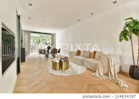 A stylish modern living room featuring elegant furniture, a plush rug, a dining area, and large windows allowing natural light to fill the space. A stylish modern living room featuring elegant furniture, a plush rug, a dining area, and large windows allowing natural light to fill the space. 124814197