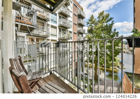 A stylish balcony overlooks a vibrant urban scenery with lush greenery nearby. The architecture blends contemporary design with nature elements. A stylish balcony overlooks a vibrant urban scenery with lush greenery nearby. The architecture blends contemporary design with nature elements. 124814226