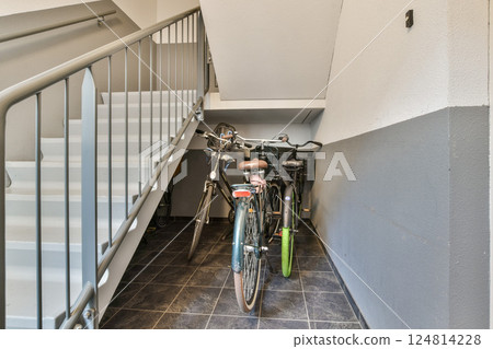 Two bicycles are parked against a wall in a stairwell, showcasing a modern and functional interior design within a residential space. 124814228