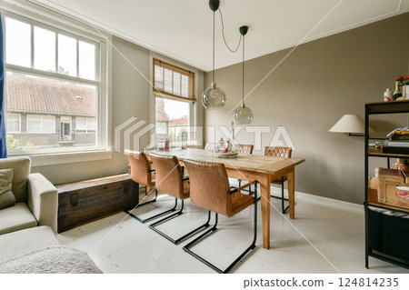 A cozy dining area featuring stylish furniture, large windows, and hanging pendant lights creating a warm atmosphere. Perfect for gatherings and everyday use. 124814235