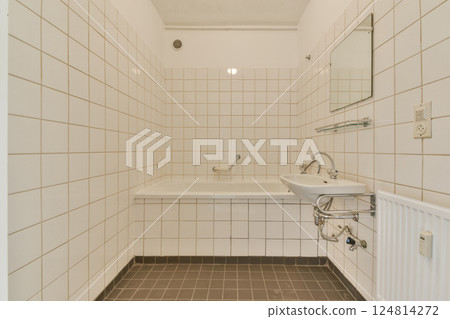 A minimalist bathroom featuring white tiled walls, a bathtub, and a sleek sink. The design emphasizes simplicity and functionality without excessive decorations. A minimalist bathroom featuring white tiled walls, a bathtub, and a sleek sink. The design emphasizes simplicity and functionality without excessive decorations. 124814272