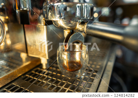 A shot of coffee flows into a glass from a coffee machine in a coffee shop. A shot of coffee flows into a glass from a coffee machine in a coffee shop. 124814282