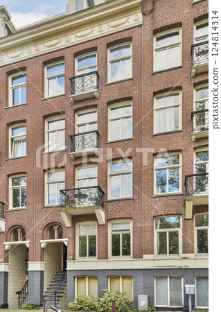 A stunning view of a modern red brick apartment building featuring large windows and decorative balconies, reflecting contemporary architectural style. 124814314