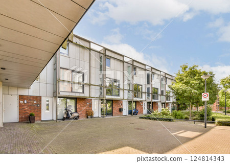 Contemporary residential buildings feature a clean design complemented by lush greenery and well-maintained walkways, showcasing urban living in harmony with nature. 124814343