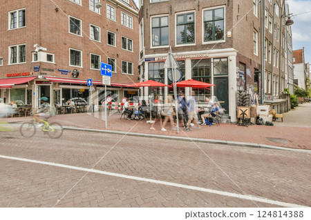 A lively urban atmosphere showcasing pedestrians, cyclists, and outdoor cafes with colorful umbrellas, capturing the essence of city life. A lively urban atmosphere showcasing pedestrians, cyclists, and outdoor cafes with colorful umbrellas, capturing the essence of city life. 124814388