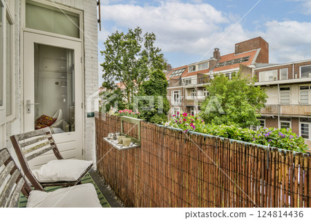A cozy balcony adorned with plants and flowers, providing a serene escape in an urban setting. The view offers a blend of nature and city architecture. 124814436
