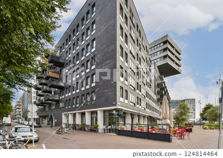 A contemporary building featuring unique angles, large windows, and a stylish outdoor seating area in an urban setting. 124814464