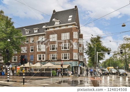 This image captures a bustling city intersection showcasing striking historical architecture under a partly cloudy sky, with pedestrians and traffic in view. 124814508